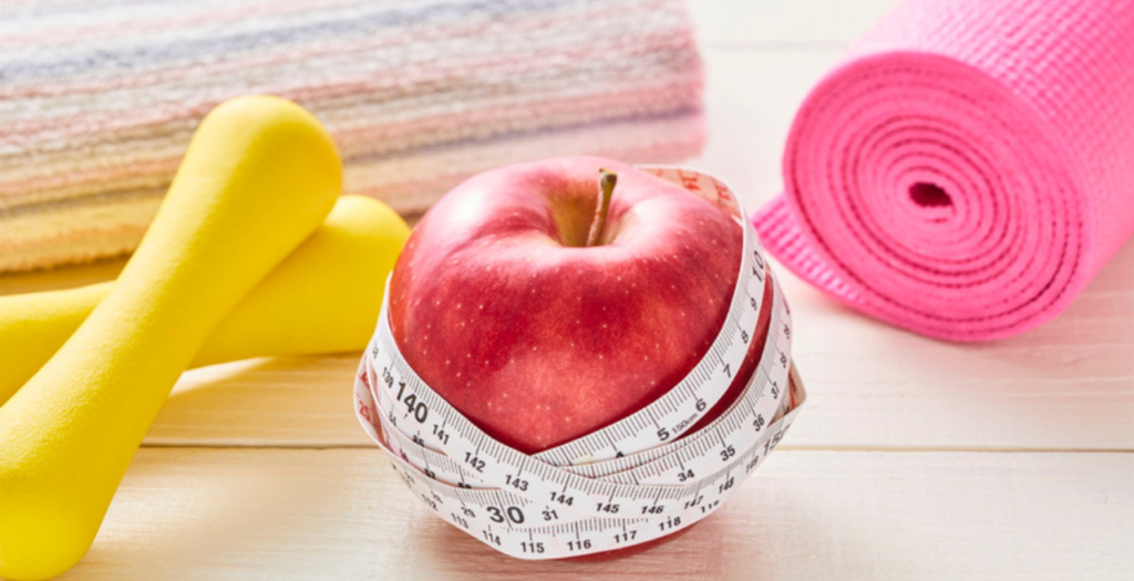 Apple, measuring tape and dumbbells, trying to lose weight in Dubai
